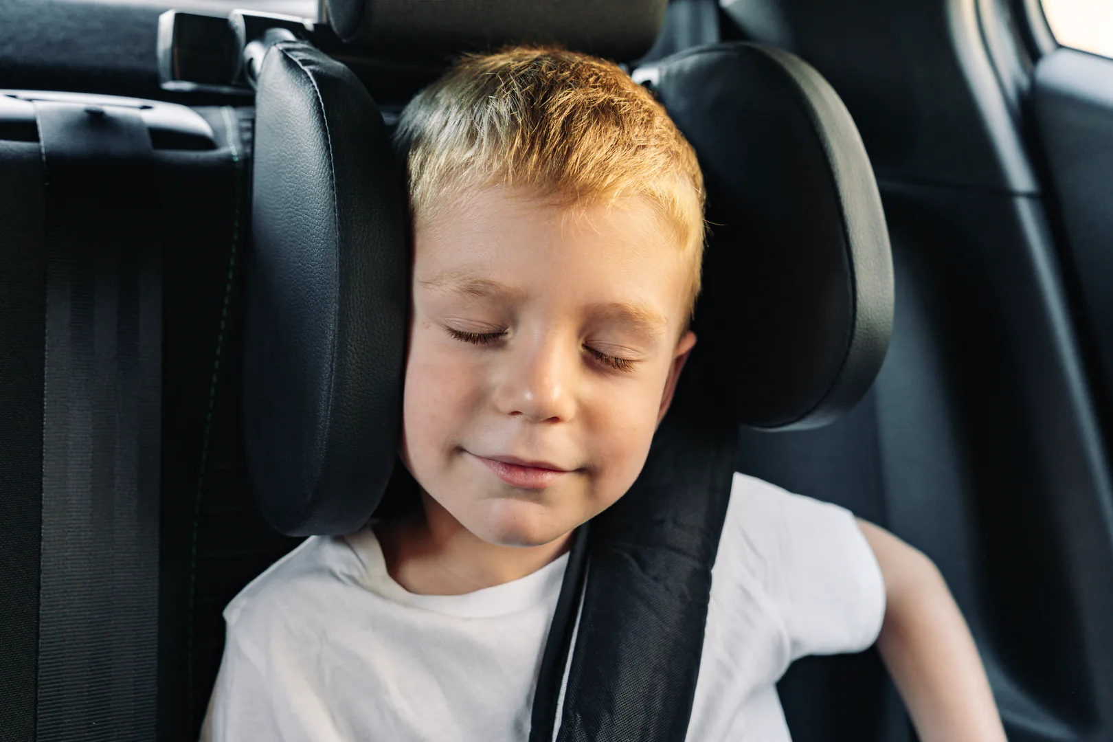 Niño descansando con un reposacabezas en el coche
